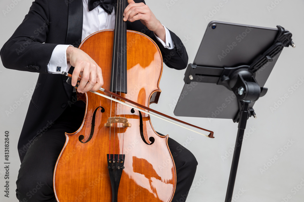 Fototapeta premium Unrecognizable man artist wearing tuxedo playing cello with music note