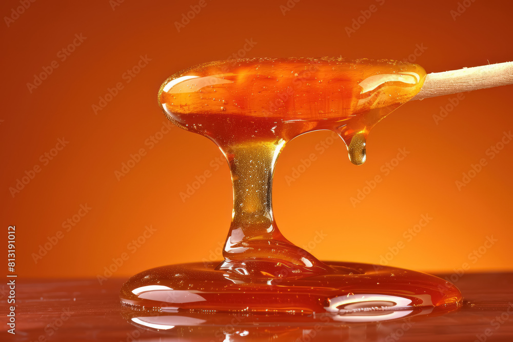 golden honey dripping from dipper on orange background golden honey dripping from dipper on orange background