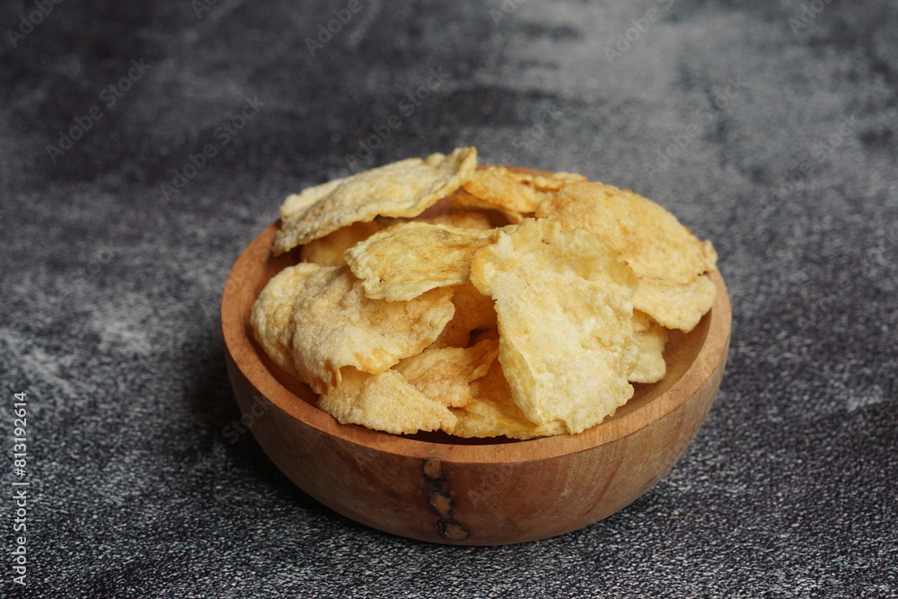 Emping, Indonesian traditional snack made from melinjo or belinjo seeds. Bitter and savory. served on wooden plate with black background Emping, Indonesian traditional snack made from melinjo or belinjo seeds. Bitter and savory. served on wooden plate with black background