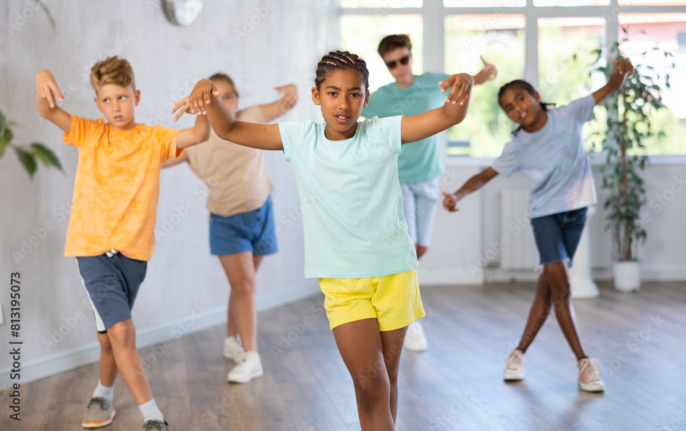Fototapeta premium Confident dark-skinned tween girl krumper posing during workout in group dance class for children..