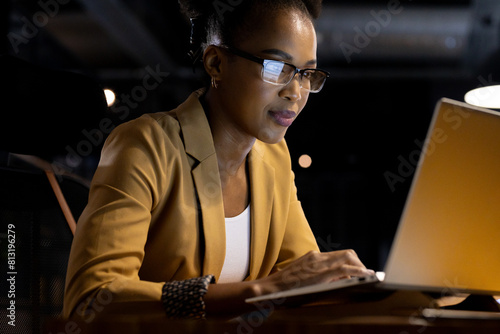 At office, African American businesswoman working late on her laptop