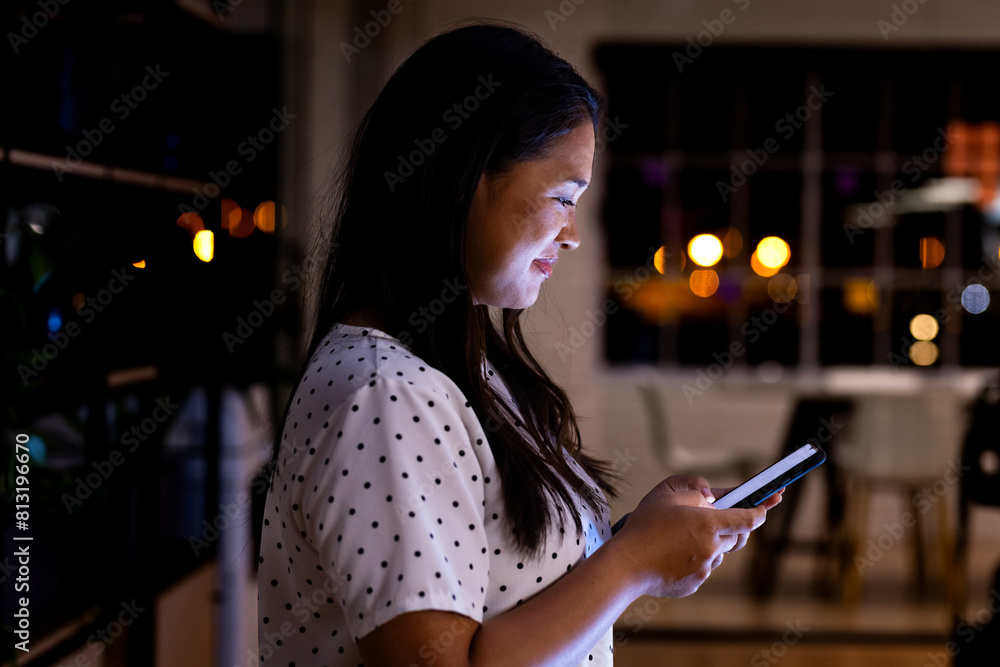 © Wavebreak Media - At office, biracial businesswoman holding smartphone, working late © Wavebreak Media - At office, biracial businesswoman holding smartphone, working late