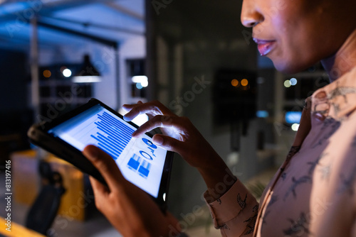 African American businesswoman reviewing data on tablet, working late