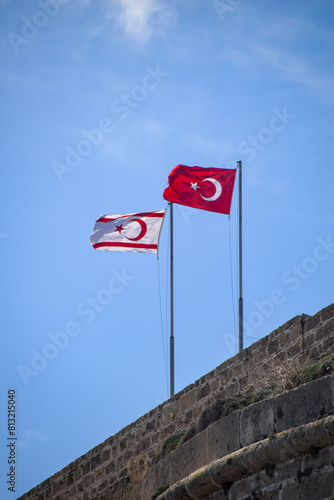 Turkey and Turkish Republic of Northern Cyprus flags waving in the blue and cloudy sky