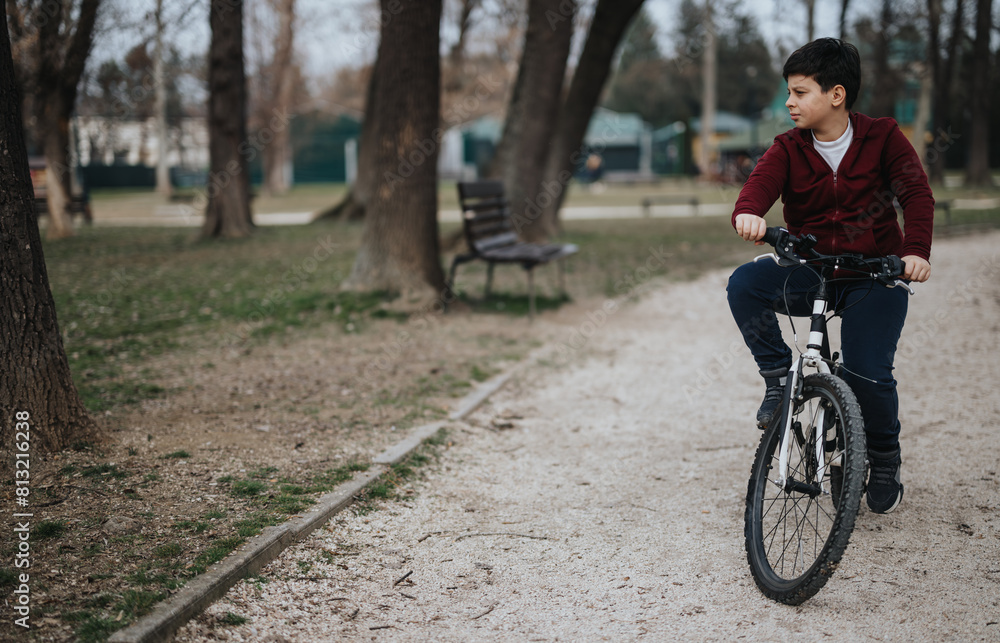 Active young kid on a bike, enjoying a joyful ride outdoors in a park setting surrounded by trees. Active young kid on a bike, enjoying a joyful ride outdoors in a park setting surrounded by trees.