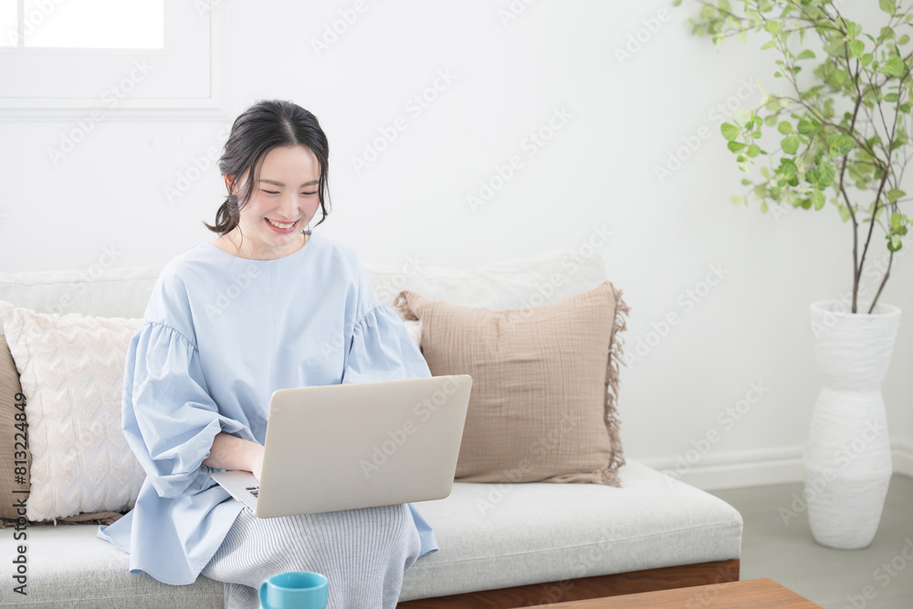 リビングで座るパソコンを使う女性 リモートワークや在宅で働く女性のイメージ リビングで座るパソコンを使う女性 リモートワークや在宅で働く女性のイメージ