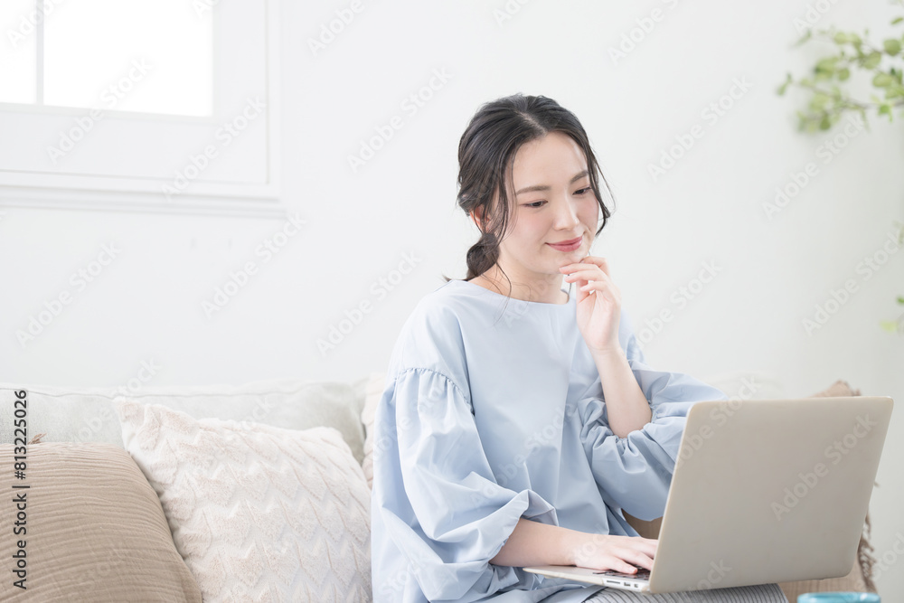 Woman using a computer sitting in the living room Image of a woman working remotely or at home Looking at a computer to search and think Woman using a computer sitting in the living room Image of a woman working remotely or at home Looking at a computer to search and think