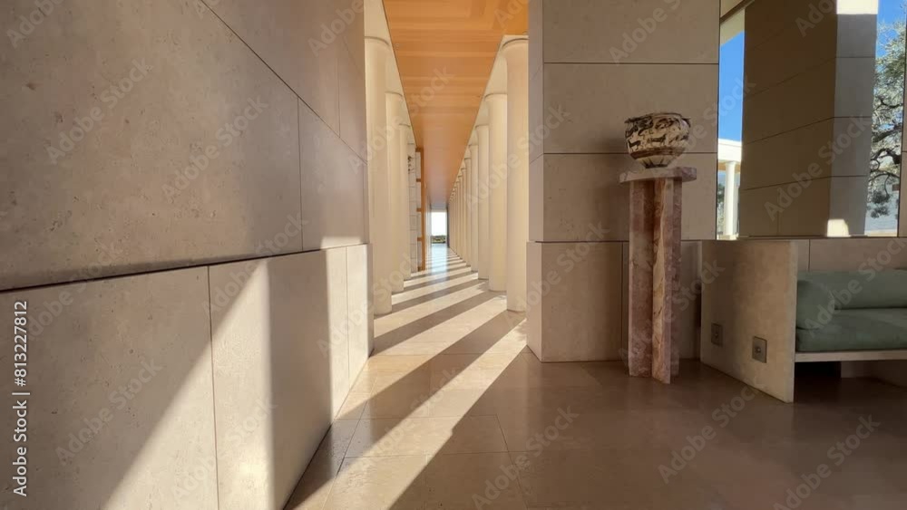 A spacious hallway featuring elegant columns, a comfortable couch, and hardwood flooring in a building made of wood fixtures and materials A spacious hallway featuring elegant columns, a comfortable couch, and hardwood flooring in a building made of wood fixtures and materials
