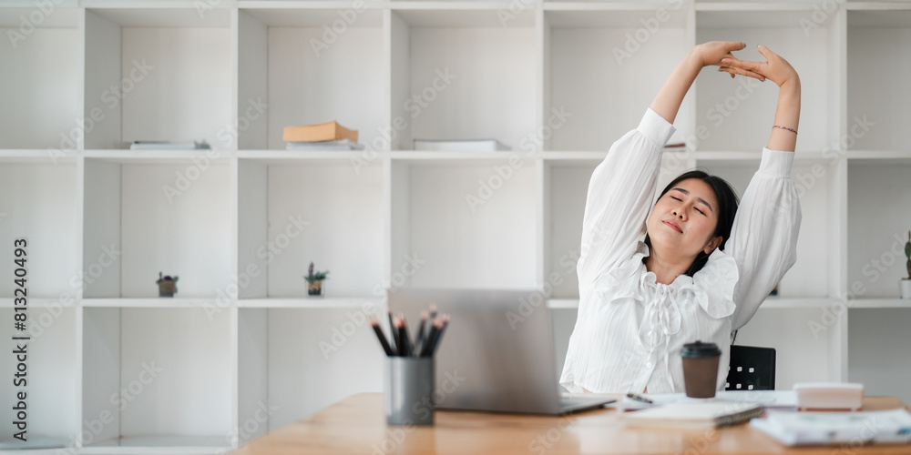 Businesswoman takes a moment to stretch and relax at her desk, in the calm atmosphere of her office. Businesswoman takes a moment to stretch and relax at her desk, in the calm atmosphere of her office.