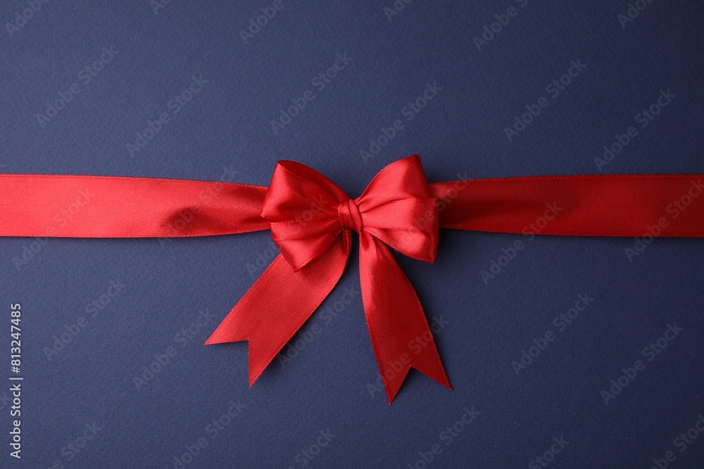 Red satin ribbon with bow on blue background, top view Red satin ribbon with bow on blue background, top view