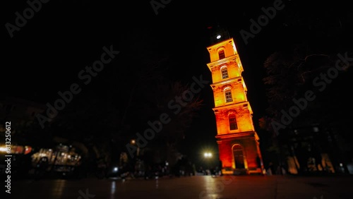 Time lapse: people are walking around fast near Tophane Clock Tower with red illumination at night in Bursa, Turkey. Historical, long exposure, timelapse and architecture concept photo