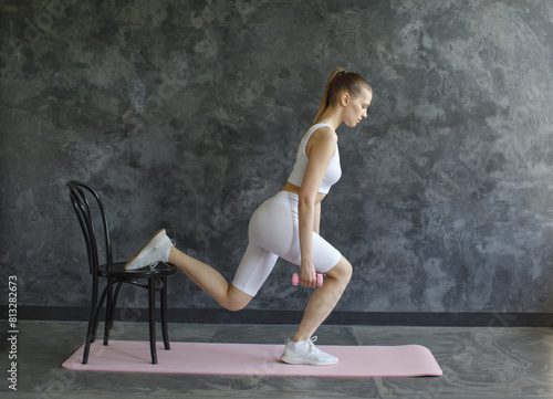 sporty woman doing lunge exercise with chair with dumbbells