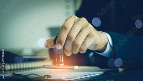 Close-up Of A Person's Hand Stamping With Approved Stamp On Document At Desk, notary or business people work from home,
Sign Approved Stamp On Document to permit and certify for work document At Desk