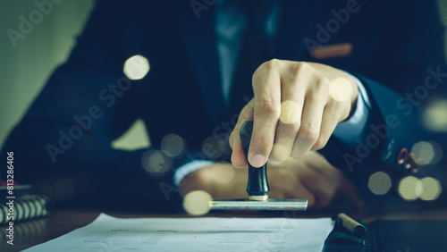 Close-up Of A Person's Hand Stamping With Approved Stamp On Document At Desk, notary or business people work from home,
Sign Approved Stamp On Document to permit and certify for work document At Desk photo