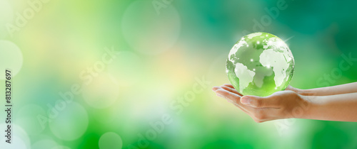 Fototapeta Naklejka Na Ścianę i Meble -  Globe crystal glass ball in hands. Green Sunny background with bokeh. World mental health and World earth day. Saving environment and World Ecology Concept.