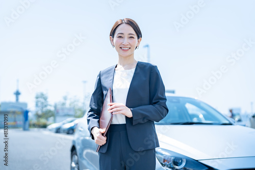 Obraz na płótnie 屋外に停めてある車の前に立つスーツを着た女性