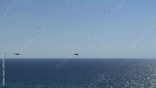 Four helicopters fly over the sea coastline