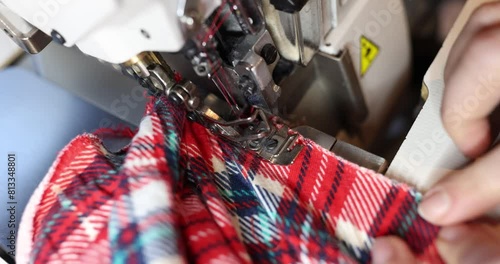 Worker sews vibrant clothing pieces using overlock machine photo
