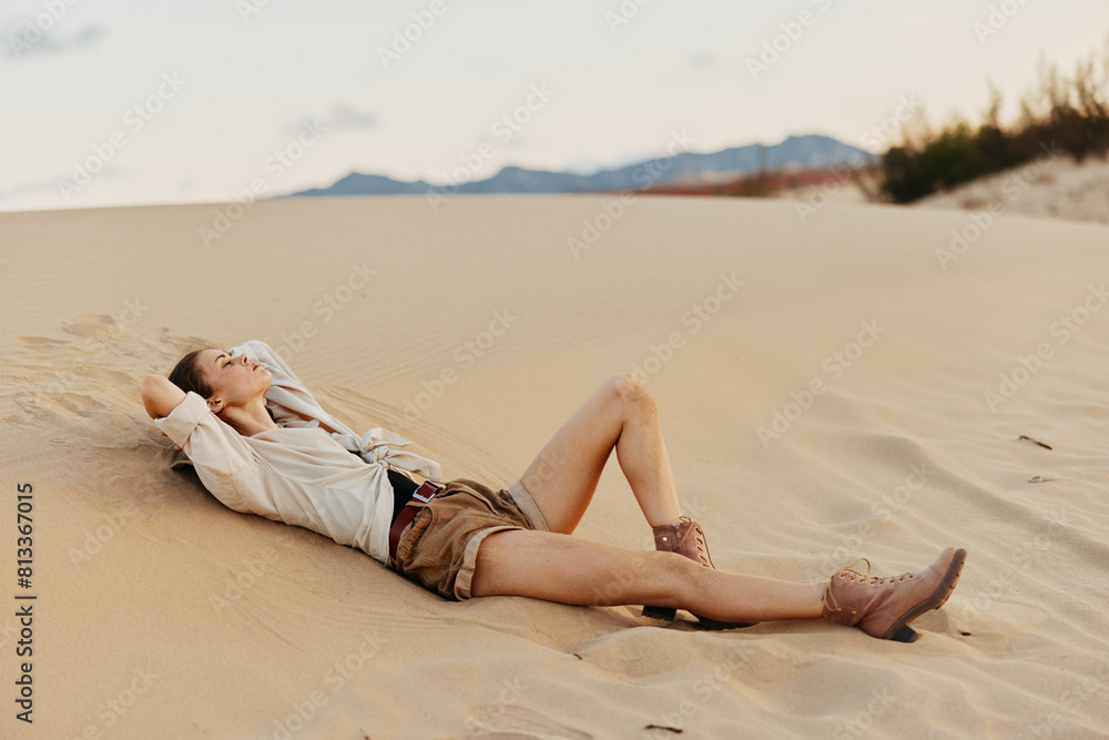 Woman relaxing in the desert with her legs up in the air, enjoying the peaceful solitude of the vast sand dunes Woman relaxing in the desert with her legs up in the air, enjoying the peaceful solitude of the vast sand dunes