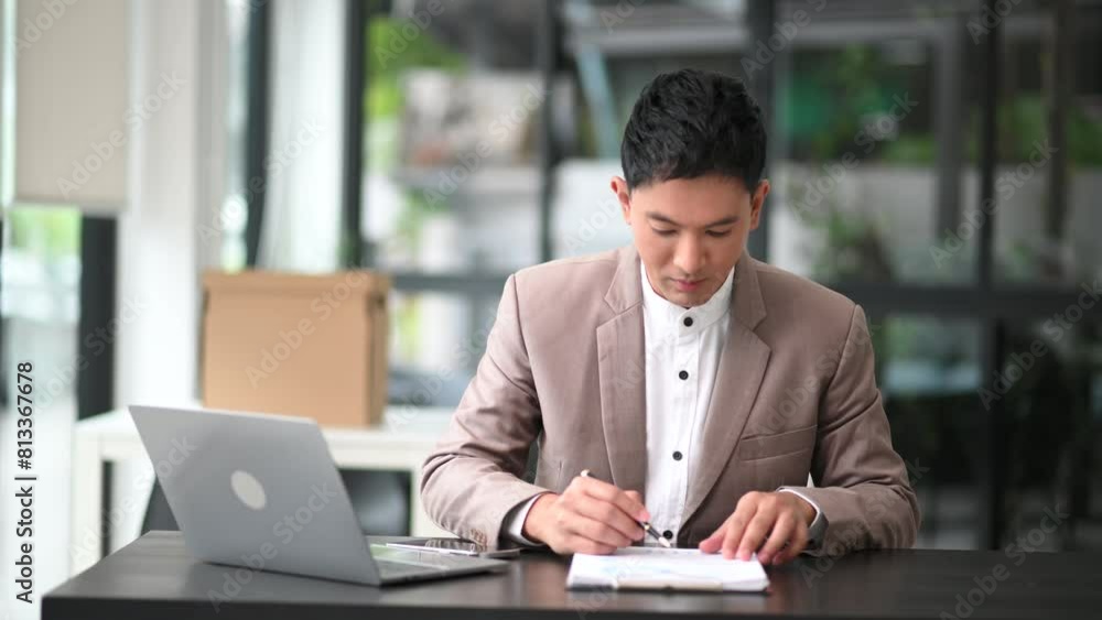 Young businessman typing on tablet and laptop while sitting at the working wooden table modern office Young businessman typing on tablet and laptop while sitting at the working wooden table modern office