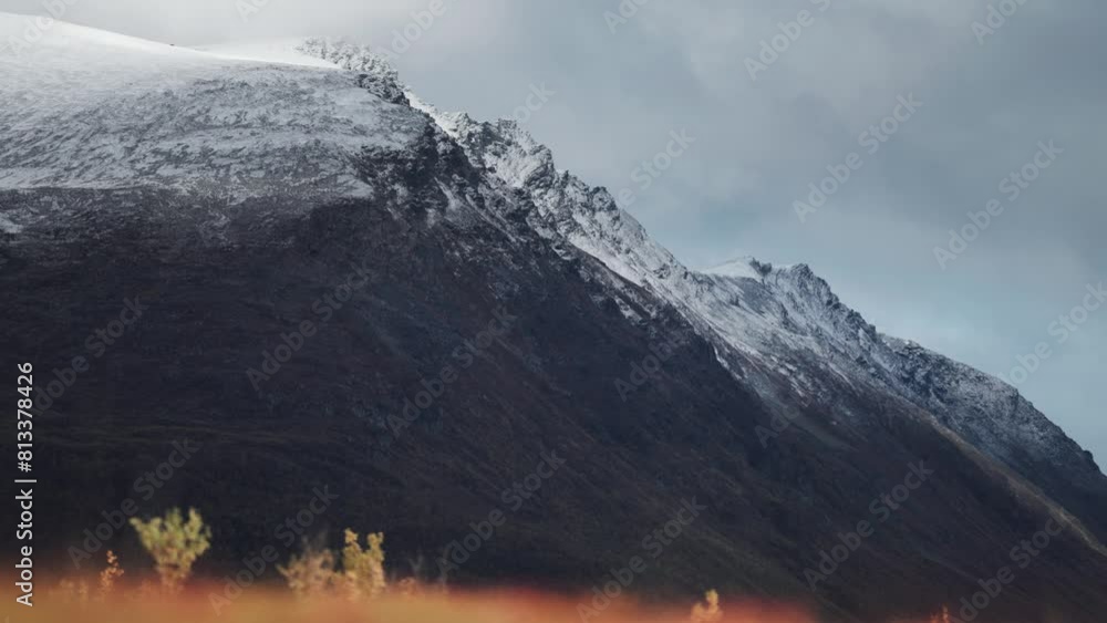 Snow-capped mountains tower above the autumn landscape.