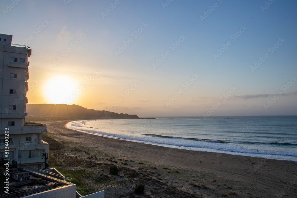 Fototapeta premium 青とオレンジのグラデーションの空になった小さな湾状の海岸の朝焼け横フレーム