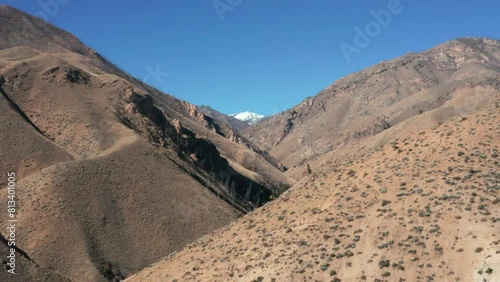 Drone footage of a remote mountainscape with brown foothills and snow capped mountain in the Frank Church River of No Return Wilderness in Idaho photo