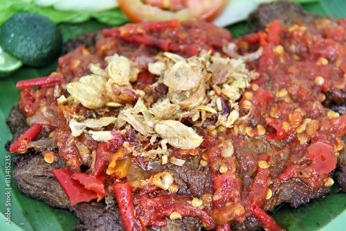 Empal Penyet consists of deep-seated beef cooked with kitchen spices such as bay leaves, galangal, lime leaves, tamarind, shallots, garlic, and many more. photo