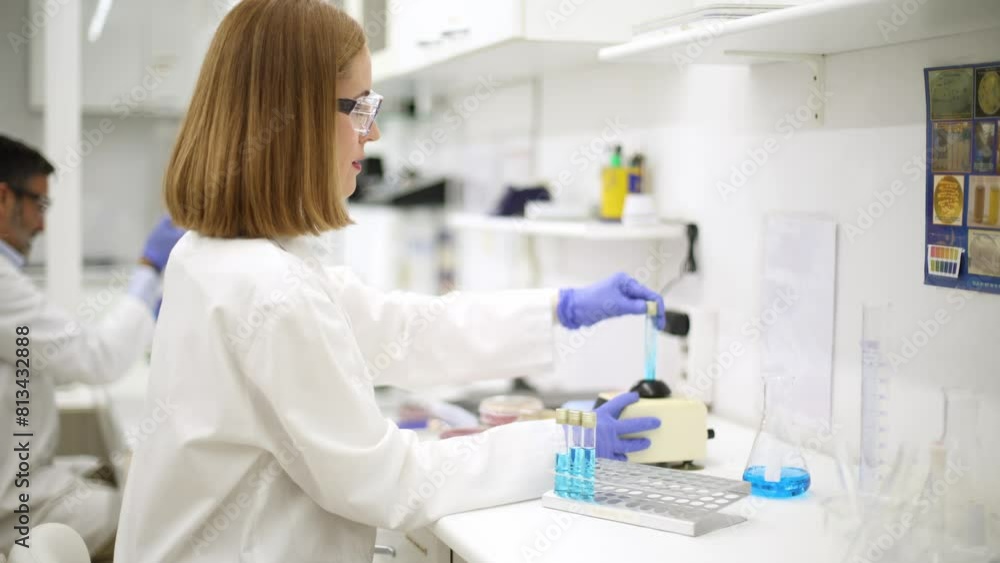 Scientist agitates sample tube in a shaker before analysis in a lab. Scientist agitates sample tube in a shaker before analysis in a lab.