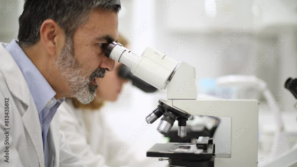 Close-up of laboratory technician looking through a microscope using a microscope Close-up of laboratory technician looking through a microscope using a microscope