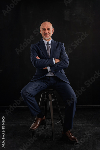Full length shot of a mid aged businessman wearing suit against isolated dark background