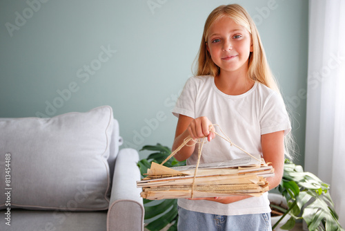 The girl is holding a stack of newspapers in her hands. Ecology. The child hands over paper for waste paper.