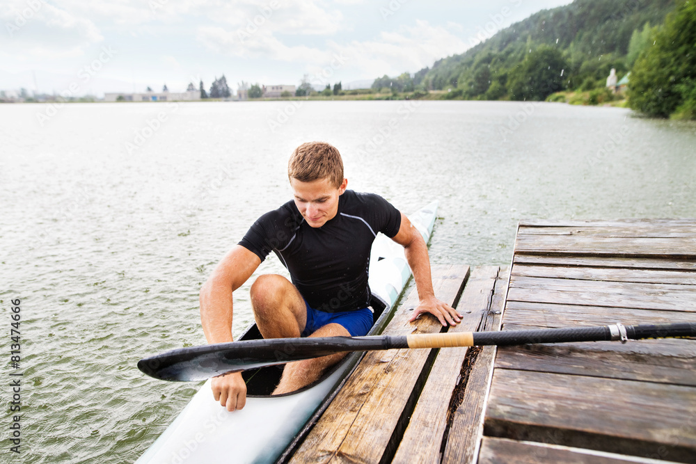 Canoeist man sitting in canoe holding paddle, getting out of water. Concept of canoeing as dynamic and adventurous sport. Canoeist man sitting in canoe holding paddle, getting out of water. Concept of canoeing as dynamic and adventurous sport.