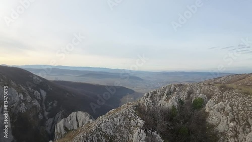 Aerial zoom out drone shot of a mountain cliff with a cross monument symbol on a clear autumn day in Turzii Gorge Romania photo