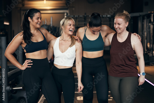 Laughing group of diverse young women in sportswear standing arm in arm together after a workout in a health club photo