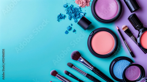 Makeup products displayed on green background including black palette with brushes and two small round containers of blue and purple powder.