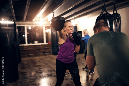 Focused woman in purple tank top, wearing protective pads working out with a boxing partner in the gym. photo