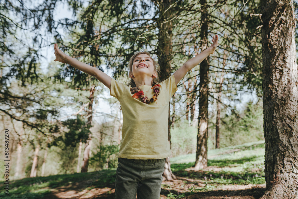 Happy girl with arms outstretched standing in forest Happy girl with arms outstretched standing in forest
