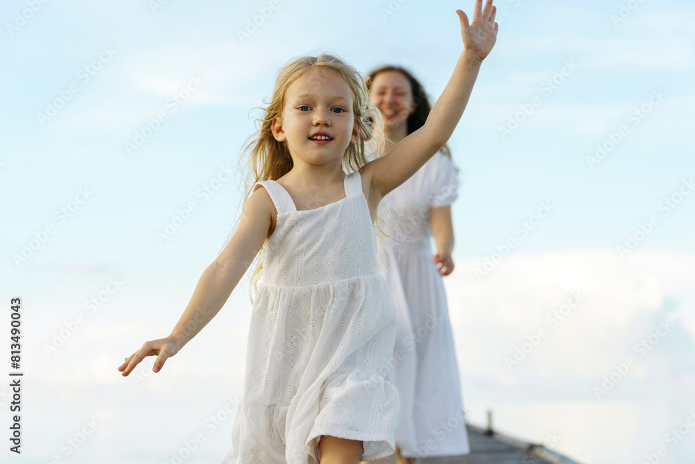 Happy girl enjoying with mother at vacations in front of sky Happy girl enjoying with mother at vacations in front of sky