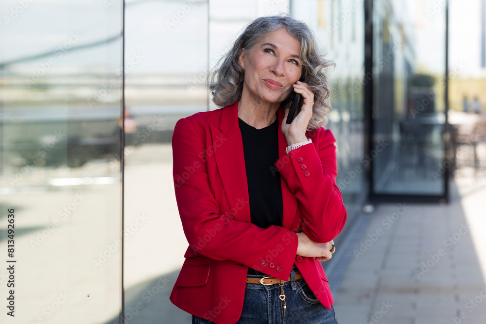 Thoughtful businesswoman talking on smart phone standing at street Thoughtful businesswoman talking on smart phone standing at street