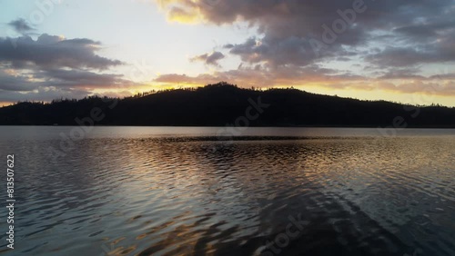 Close aerial flyover of the waters of Whiskeytown Lake in Northern California towards a sunrise backlit mountain. photo