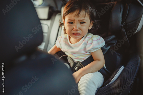 crying toddler girl sitting in car seat, safety baby chair travelling