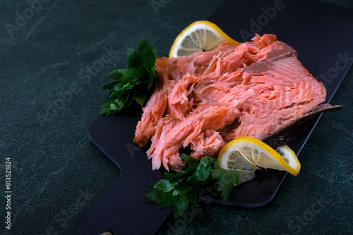 Hot smoked trout fillet served on the black board with lemon and parsley