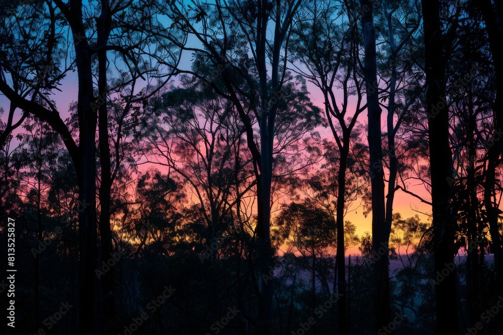 Obraz premium A row of trees with a purple sky in the background