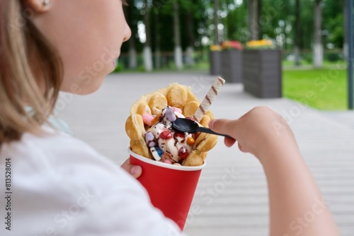 Hong Kong or bubble waffles with ice cream, chocolate tubes and marmalade in the hands of a child photo
