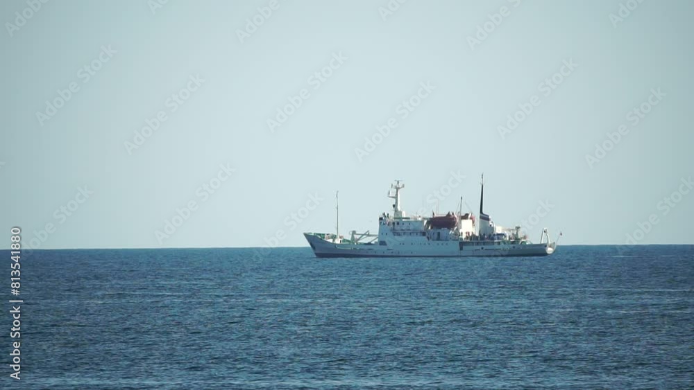 Fishing boat trawler catches fish while sailing on sea. A commercial fishing boat on the horizon in a distance sail to catch school of fish on calm sea surface in summer. Commercial catch of sea fish. Fishing boat trawler catches fish while sailing on sea. A commercial fishing boat on the horizon in a distance sail to catch school of fish on calm sea surface in summer. Commercial catch of sea fish.