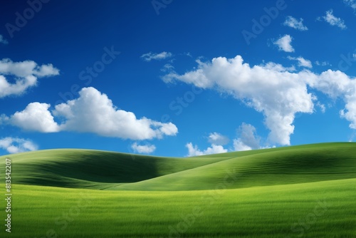 A beautiful summer or spring landscape with green grass on the hills and green fields. The blue sky is filled with white clouds and bright sunlight. Nature as a background.