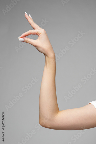 Female hand gesturing sign against gray background