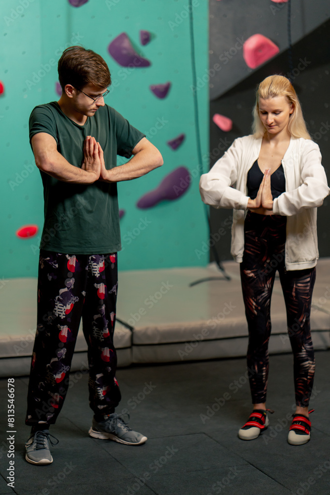 Obraz premium young girl at a climbing wall with a trainer doing a warm-up before rock climbing training