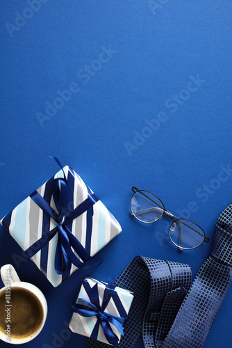 Gift Set on Blue. Top view of a neat gift arrangement with two wrapped presents, eyeglasses, a coffee cup, and a rolled tie on a elegant blue background. Ideal for gifting and celebration themes. © photoguns